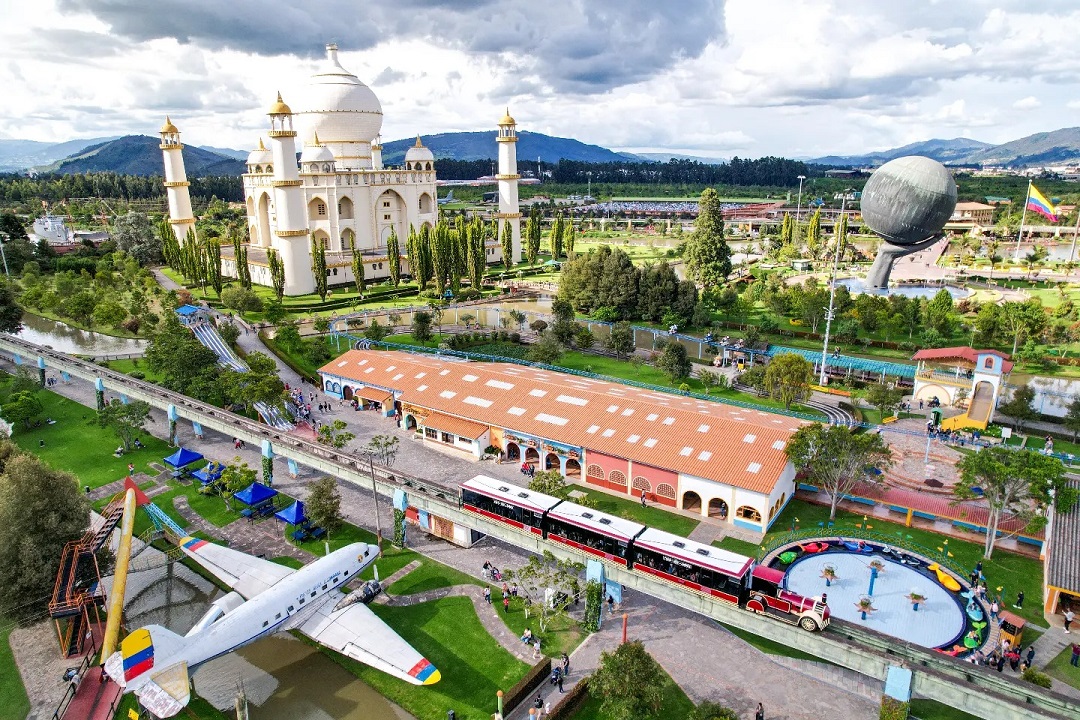 Un tren pasando en vías al lado de un edificioDescripción generada automáticamente